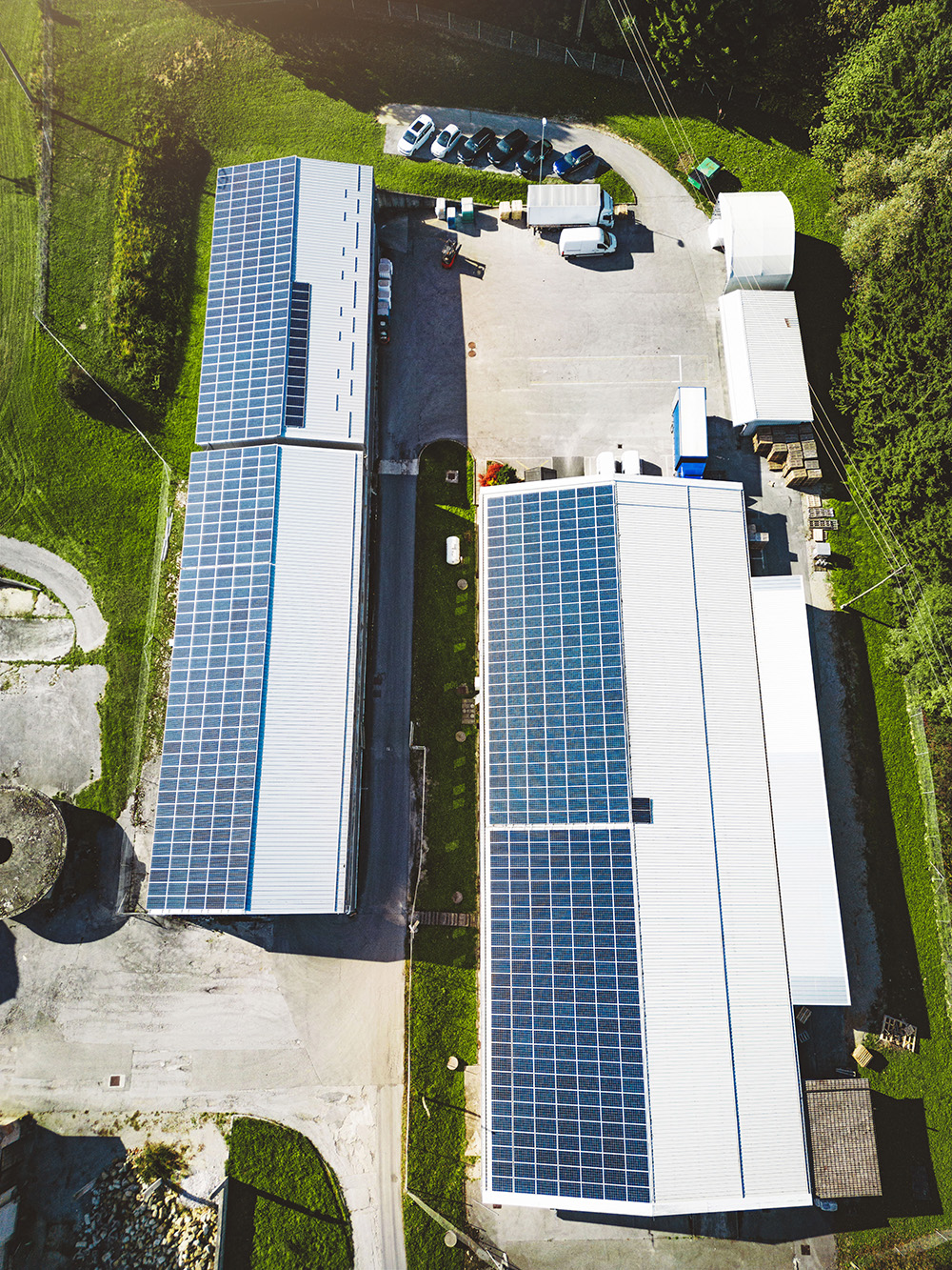 vertical photo top down aerial view solar panels roof two warehouses countryside
